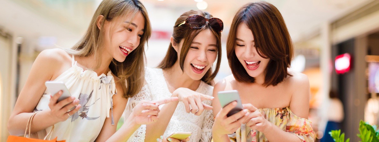 Asian-American women watching smart phone in shopping mall
