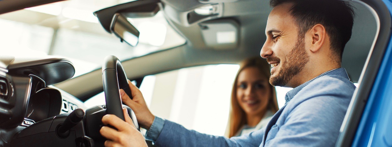 Young couple choosing new car for buying in dealership shop