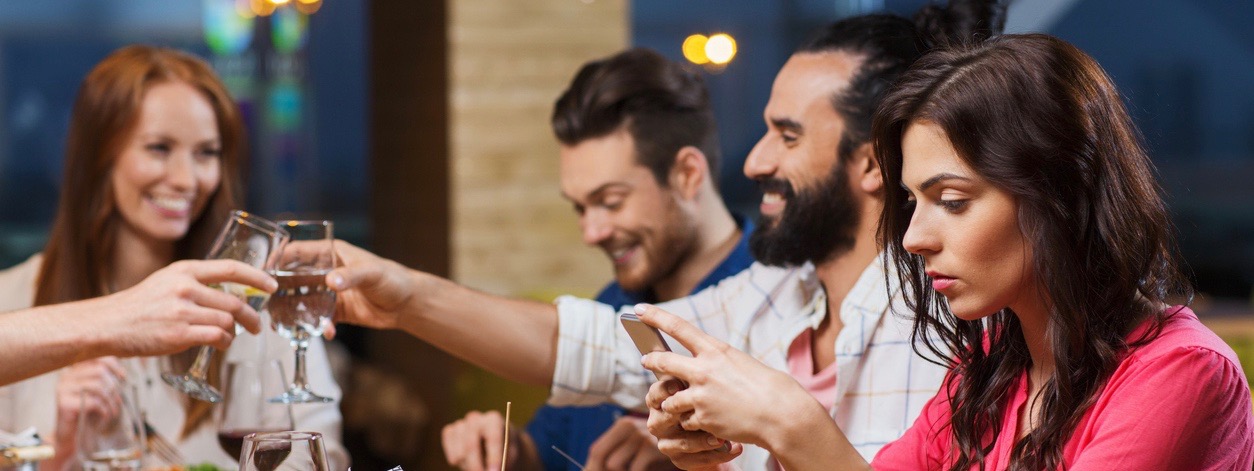 woman with smartphone and friends at restaurant