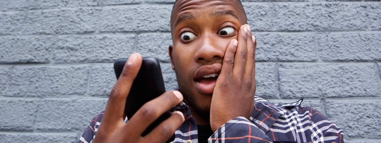 Young african man reading bad message on his mobile phone