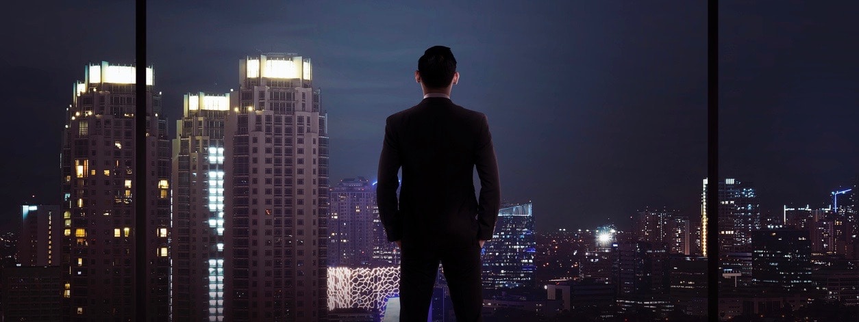Man standing in his office looking at the city