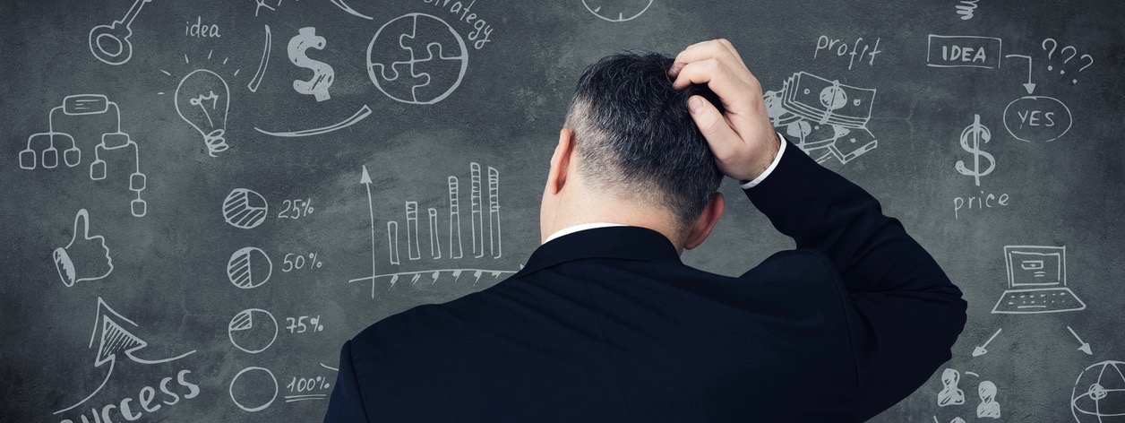 Rear view of pensive mature man scratching his head and looking at digitally composed business signs and charts on chalkboard