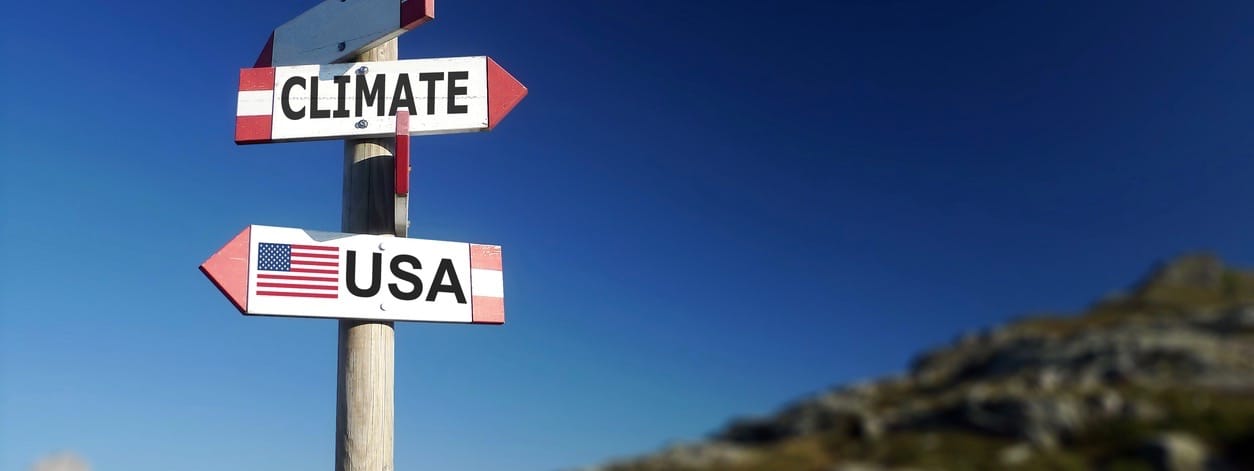 Climate change and American flag in two directions on road sign. Withdrawal of climatic agreement.