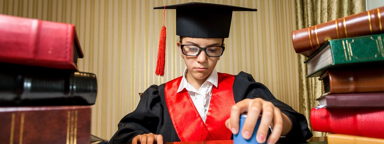 Serious clever girl in graduation cap playing in lawyer and putting stamp on document