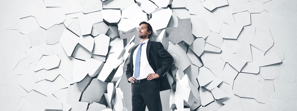 Young businessman breaking trough a wall