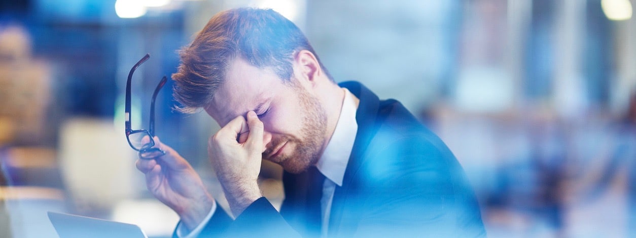 Young tired businessman sitting with his head over laptop