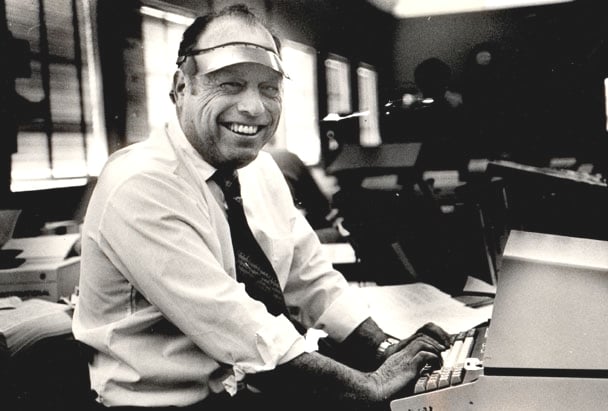 news editor at his typewriter wearing a visor