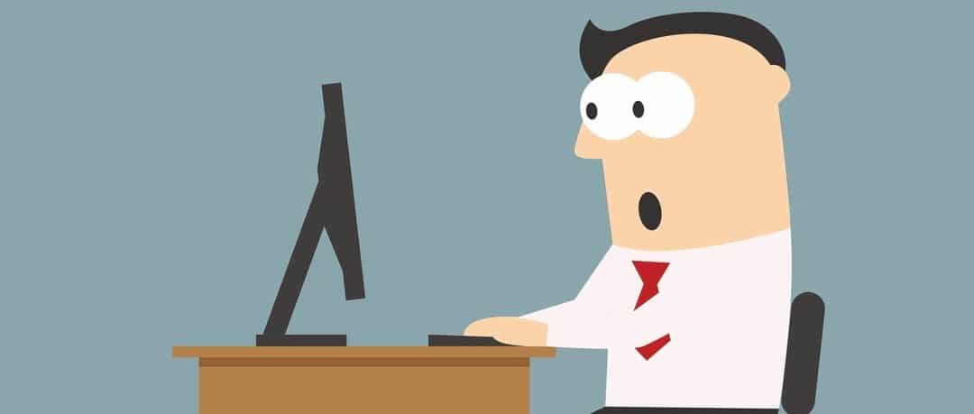 Shocked businessman sitting on his workplace and looking at the monitor screen. He reading something unbelievable. Surprise, shock, amazement, emotion and expression concept usage