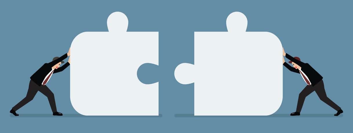 Businessmen pushing two jigsaw pieces together. Business teamwork