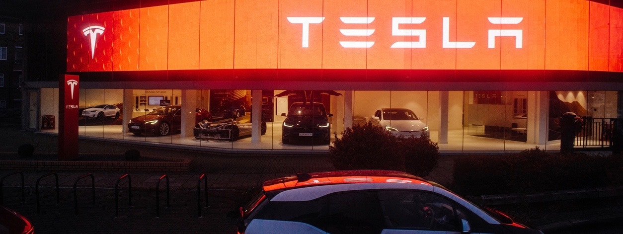 Street view of Tesla motors showroom with cars inside and illuminated logo brandin at dusk London UK