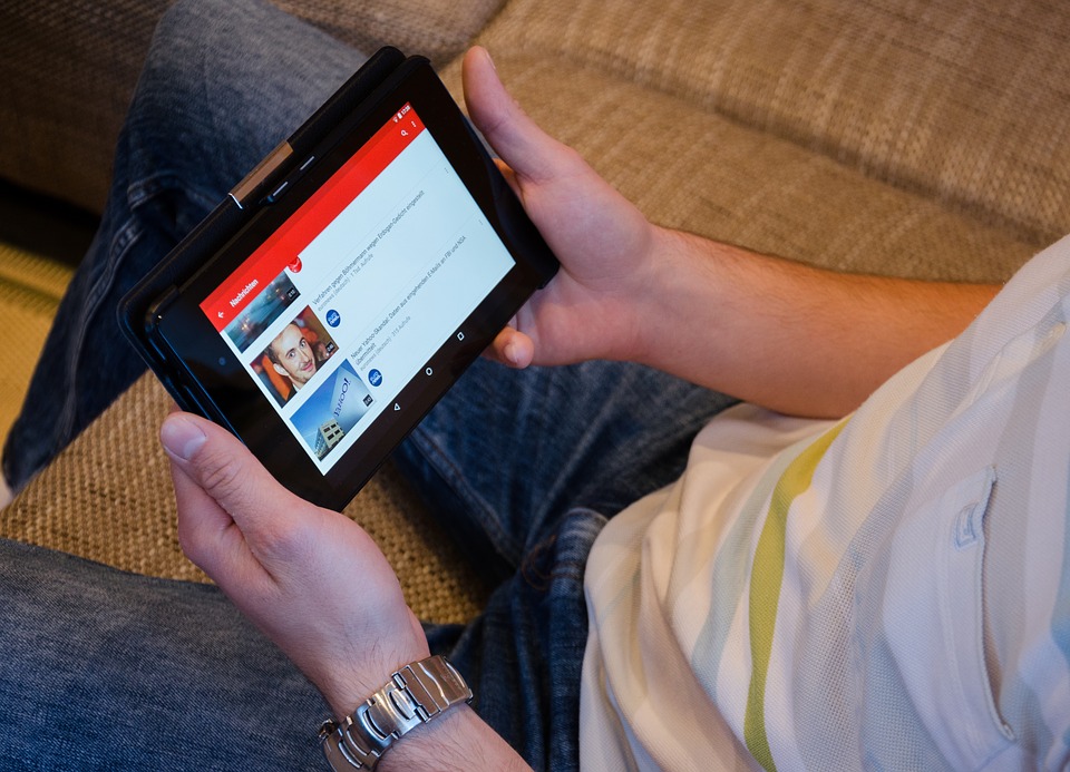 Man holding a tablet and watching YouTube.