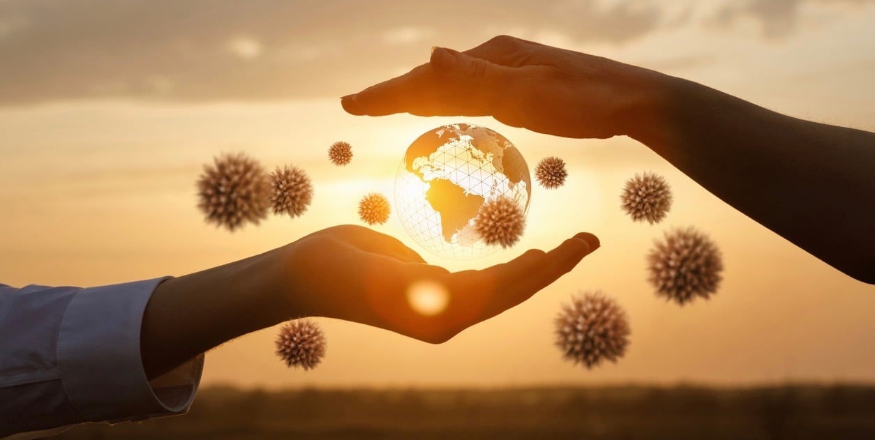 The concept of protecting the world from coronavirus. Hands protects the globe from viruses against the backdrop of a sunny sunset.