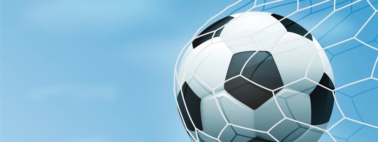Soccer ball in goal net with blue sky.