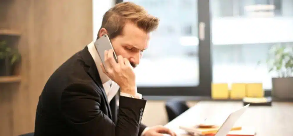 A man having a phone call in front of his laptop 